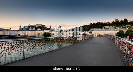 Amore si blocca su Makartsteg ponte sopra il fiume Salzach, con la città vecchia a distanza, Salisburgo, l'Austria, l'Europa. Presi la mattina presto. Foto Stock