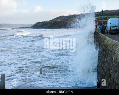 Mare mosso e le onde si infrangono contro la parete del mare sul lungomare durante il tempo ventoso a marea alta. Benllech, Isola di Anglesey, Galles, Regno Unito, Gran Bretagna Foto Stock