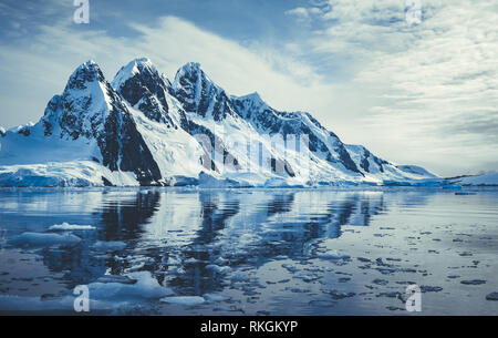 Ghiaccio montagne coperte in oceano polare. In inverno il paesaggio antartico in bianco e blu le tinte. Il monte è riflesso nell'acqua cristallina. Il cloud computing Foto Stock