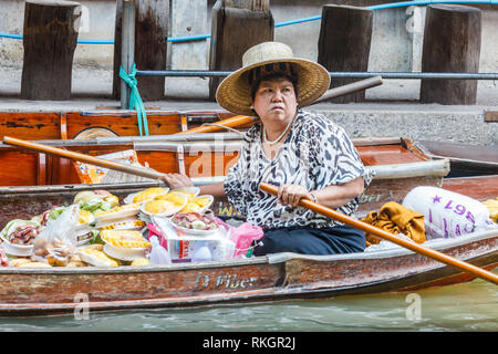 Damnoen Saduak, Tailandia - 4 Marzo 2017: fornitore di frutta pagaie la sua barca. Il mercato galleggiante è una meta turistica molto atrraction Foto Stock