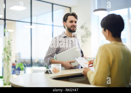 Programmatore di giovani parlando alla reception Foto Stock