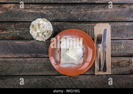 Strudel con un apple e gelato alla vaniglia, servita su piastra in ceramica con le posate e il bicchiere di bevanda. Foto Stock