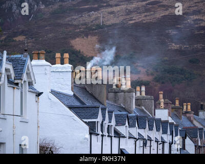 Fumo e camini domestici su una fila di case a schiera in Shore Street, Ullapool, Highland, Scozia Foto Stock