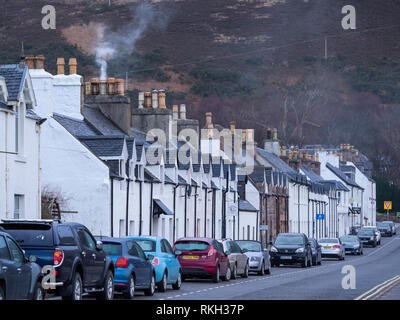 Macchine parcheggiate e case a schiera in Shore Street sul lungomare a Ullapool, Highland, Scozia Foto Stock