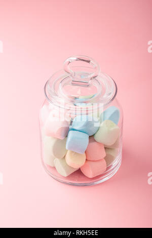 Vaso riempito con colorati marshmallows su sfondo semplice Foto Stock