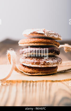 A pochi gingerbread cookies avvolto in nastro su un tavolo di legno. Sfondo semplice. Orientamento verticale Foto Stock