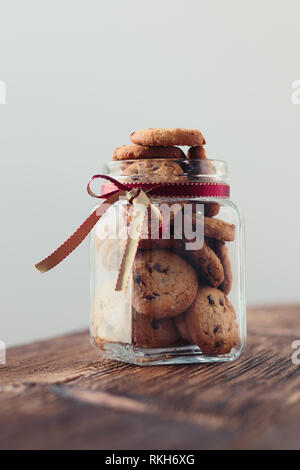 Grande vaso riempito con oat i cookie in piedi su un tavolo di legno. Sfondo semplice. Orientamento verticale Foto Stock