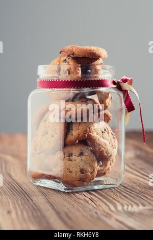 Grande vaso riempito con oat i cookie in piedi su un tavolo di legno. Sfondo semplice. Orientamento verticale Foto Stock