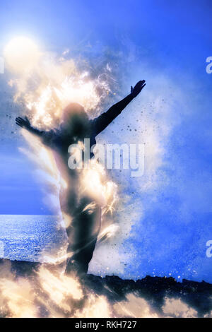 Una donna sola alzando le braccia spiritualmente sul fuoco di fronte a un potente onda a strapiombo sul mare Foto Stock