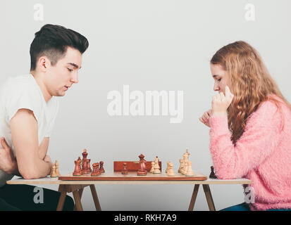 Ragazzo e una ragazza a giocare a scacchi a casa, essi sono concentrati sulle loro prossime mosse. Gli adolescenti seduti a un tavolo. Vista di profilo. Copia spazio per il testo nel Foto Stock