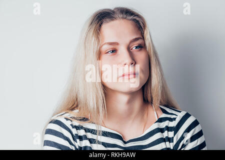 Giovane bella donna tristi e gravi in questione cercando riposo e riflessivo espressione facciale, sentirsi depressi su sfondo bianco. Emotio negativa Foto Stock