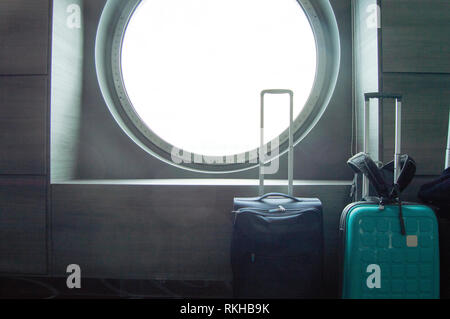 Due valigie per viaggiare nella parte anteriore del round di oblò della nave, il concetto di viaggio di piacere o di lavoro Foto Stock