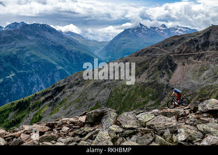 Un uomo corse in mountain bike su un sentiero roccioso nel villaggio austriaco di Sölden nella Valle Ötztal durante i mesi estivi. Foto Stock