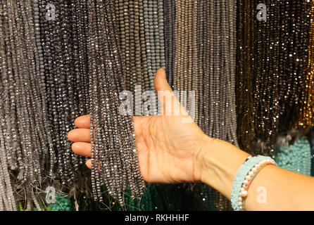 La mano della donna che sceglie le collane in costume gioielleria Foto Stock