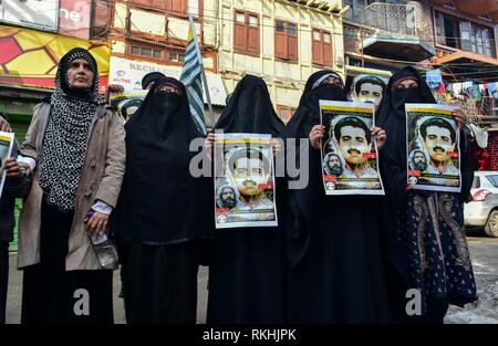 I membri dei Mussulmani Khawateen campo Markaz tenere i manifesti con ritratto di Maqbool Bhat durante una manifestazione di protesta a Srinagar, India Kashmir amministrato. Coprifuoco-simili restrizioni sono state imposte in parti di Srinagar città al seguito di una chiamata per sciopero dei gruppi separatisti per commemorare l anniversario della morte di Maqbool Bhat, il Jammu e Kashmir Liberation Front (JKLF) fondatore che fu impiccato su Feb 11, 1984 in Delhi di Tihar è prigione. Il separatista leader e attivisti in scena una protesta esigente indietro le spoglie mortali di uccisi Maqbool Bhat. Foto Stock