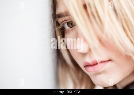 Giovane donna bionda, adolescente, appoggia la testa contro il muro di cemento, Nord Reno-Westfalia, Germania Foto Stock