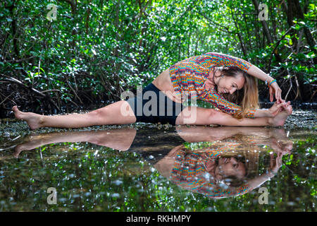 Giovane donna a praticare yoga (trampolo Split) in un ambiente naturale - Fort Lauderdale, Florida, Stati Uniti d'America Foto Stock