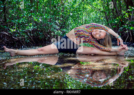 Giovane donna a praticare yoga (trampolo Split) in un ambiente naturale - Fort Lauderdale, Florida, Stati Uniti d'America Foto Stock