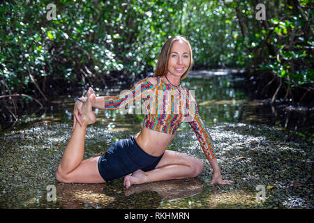 Giovane donna a praticare yoga (One-Legged re Pigeon - Eka Pada Rajakapotasana) in un ambiente naturale - Fort Lauderdale, Florida, Stati Uniti d'America Foto Stock