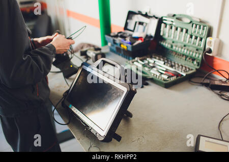 Autofficine mantiene un veicolo con la guida di un computer diagnostico - tecnologia moderna per la riparazione auto shop Foto Stock