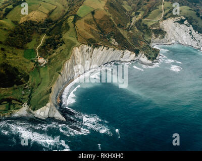 Ondulazione del mare nei pressi di colline verdi Foto Stock