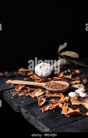 Aglio, frutta secca e semi di rustico scuro dello sfondo. Foto artistiche di aglio e frutta secca su una vecchia tavola nera girato in chiave di basso stile ciaroscurro Foto Stock