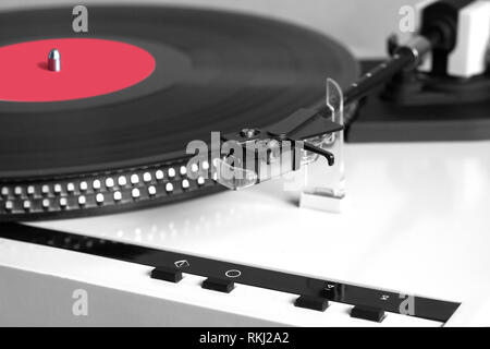 Tavola rotante in caso d'argento la riproduzione di un disco in vinile con etichetta rossa. Foto orizzontale isolato su sfondo nero in primo piano Foto Stock