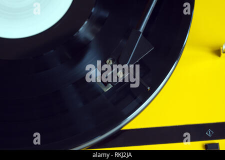 Tavola rotante in caso di colore giallo con il nero tonearm la riproduzione di un disco in vinile con etichetta bianca. Foto orizzontale top view closeup Foto Stock