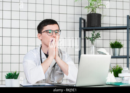 Preoccupati medico maschio utilizzando un computer portatile nella sua pratica Foto Stock