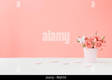 Bouquet di corallo fiori di garofano in un vaso su un sfondo di corallo. Spazio vuoto per il testo Foto Stock