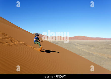 Giovane ragazzo caucasico giocando sulle dune di sabbia a Sossusvlei in Namibia Foto Stock