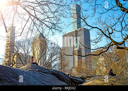 Persone appendere fuori del bel tempo su una grande roccia nel Central Park di New York con grattacieli in background Foto Stock
