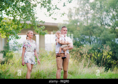 Famiglia giovane con un piccolo pianto toddler boy nella soleggiata estate natura. Foto Stock