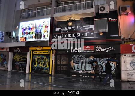 Izmir, Turchia. Xxi gen, 2019. Un uomo e una donna ombrelli azienda a piedi passato un graffiti dipinti su un pull-down otturatore. Credito: Altan Gocher | in tutto il mondo di utilizzo/dpa/Alamy Live News Foto Stock
