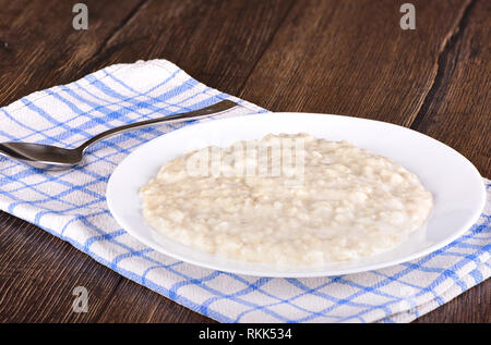 Cucinata fresca di farina di avena in una piastra su un tavolo di legno Foto Stock