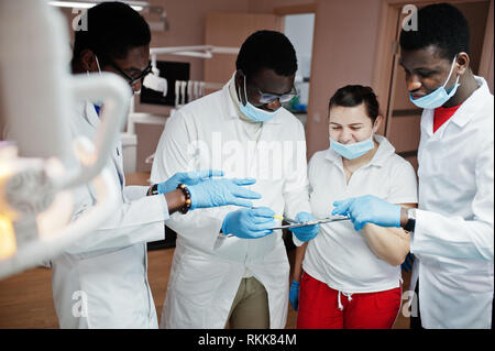 Multirazziale dentista medici team. Tre americano africano medici di sesso maschile con un medico caucasico femmina. Discussione dei momenti di lavoro. Foto Stock