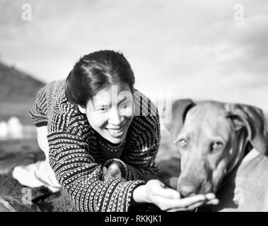 Metà donna adulta giocare felicemente con cane fuori. Foto Stock