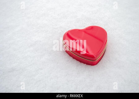 Cuore rosso scatola sagomata su uno sfondo innevato. Minimalista per il 14 febbraio. Foto Stock