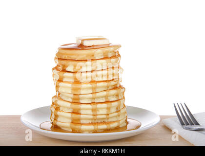 Fluffy pancakes impilati alta, burro e sciroppo, sulla piastra di porcellana sulla luce di una tavola di legno. Forcella e tovagliolo accanto, isolato su bianco. Foto Stock