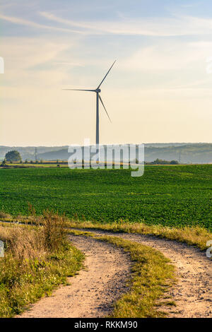 Il mulino a vento per la produzione di energia elettrica è circondato da campi agricoli in polacco paese lato. Pomerania, Polonia. Foto Stock