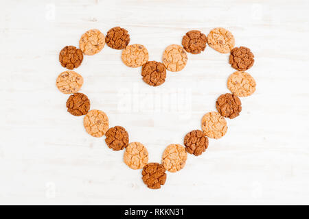 I cookie stabiliti a forma di cuore in legno su sfondo bianco. Foto Stock