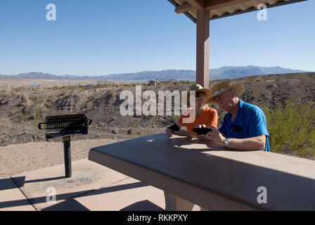 Caucasian Senior Couple (età 60-70) controllare le immagini del cellulare mentre si rilassa nella Lake Mead Recreation Area, Nevada, USA. Foto Stock