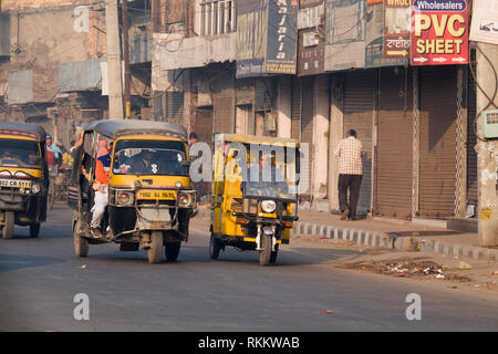 La benzina e elettrico più piccolo auto rickshaw fianco a fianco in movimento di Amritsar Punjab, India Foto Stock