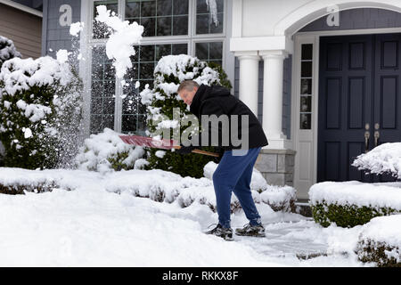 Uomo maturo spalare la neve davanti a casa il marciapiede Foto Stock