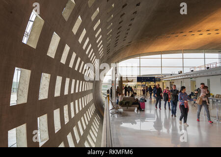 Aeroporto Charles de Gaulle di Parigi - 12/22/18: interno del terminal 2F, edificio in cemento di architettura con motivi geometrici e fori a parete. Passeggeri a piedi da w Foto Stock