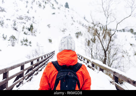 Donna in inverno una giacca calda e grigio cappello di lana con zaino a piedi nella neve montagne d'inverno Foto Stock