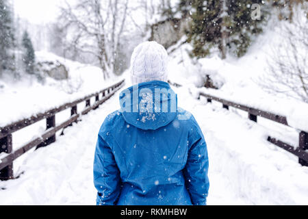 Donna in inverno una giacca calda e Bianca Cappello di lana a piedi nella neve montagne d'inverno Foto Stock