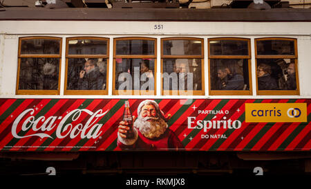 Lisbona, Portogallo - 01/03/19: Tradizionale giallo vecchio tram elettrico nel centro di Lisbona. Vista laterale con passeggeri e windows, vino Coke, Coca-cola adve Foto Stock