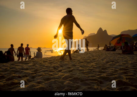 Beachgoers passeggiare e socializzare un pomeriggio estivo sulla spiaggia di Ipanema a Rio de Janeiro in Brasile Foto Stock