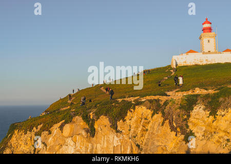 Sintra, Portogallo - 01/05/19: Cape Roca lighthouse (Cabo da Roca) verde erba, cielo blu oceano Atlantico, luogo più occidentale dell'Europa. Un sacco di gente. Foto Stock